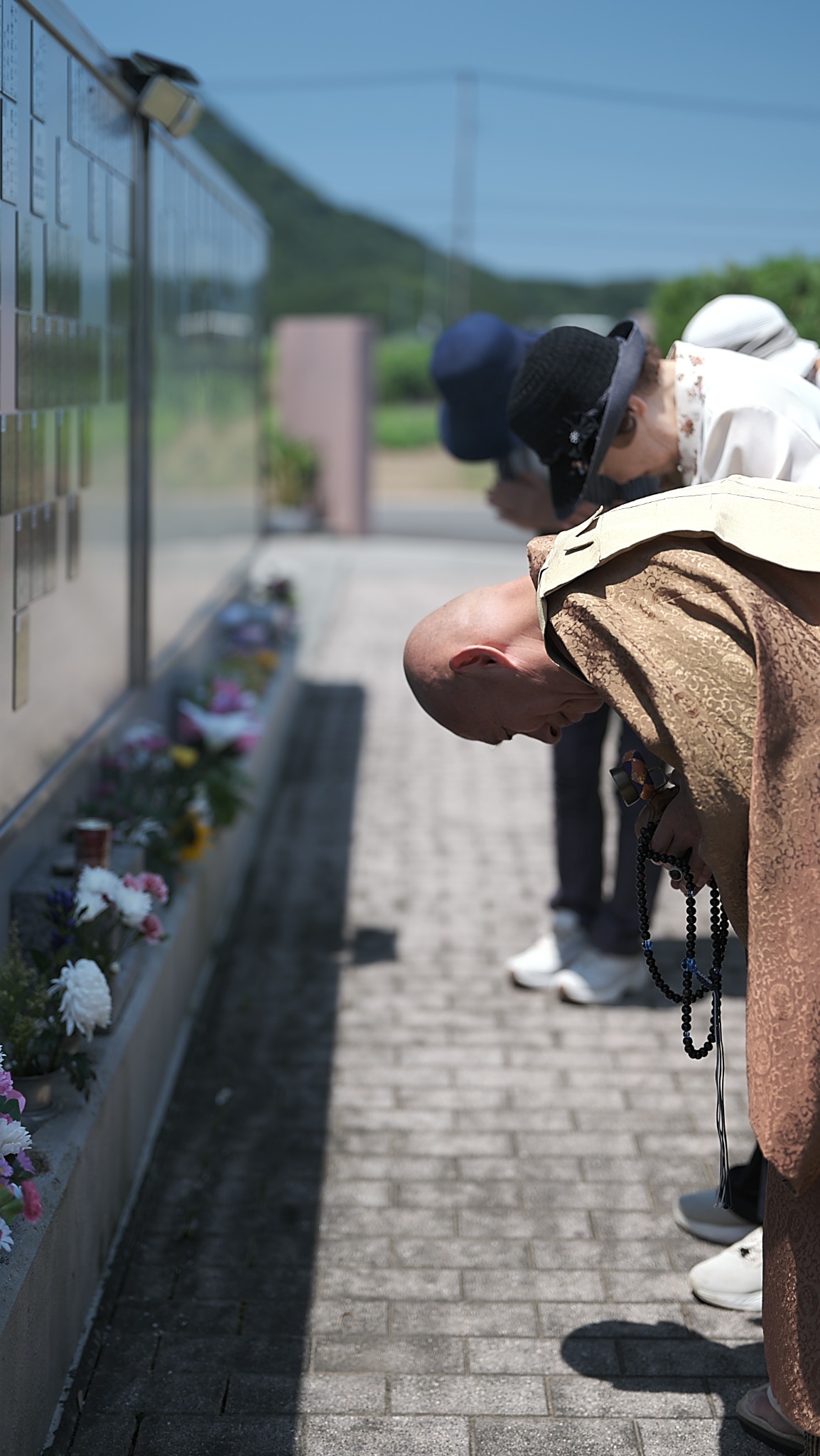 数珠を手に墓前で深く頭を下げる僧侶