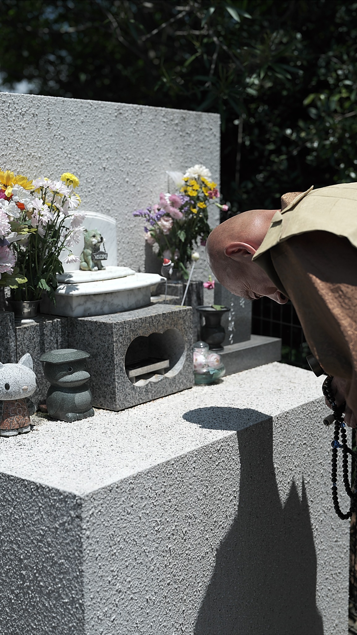 小さな供養墓の前で僧侶が頭を下げて祈る様子